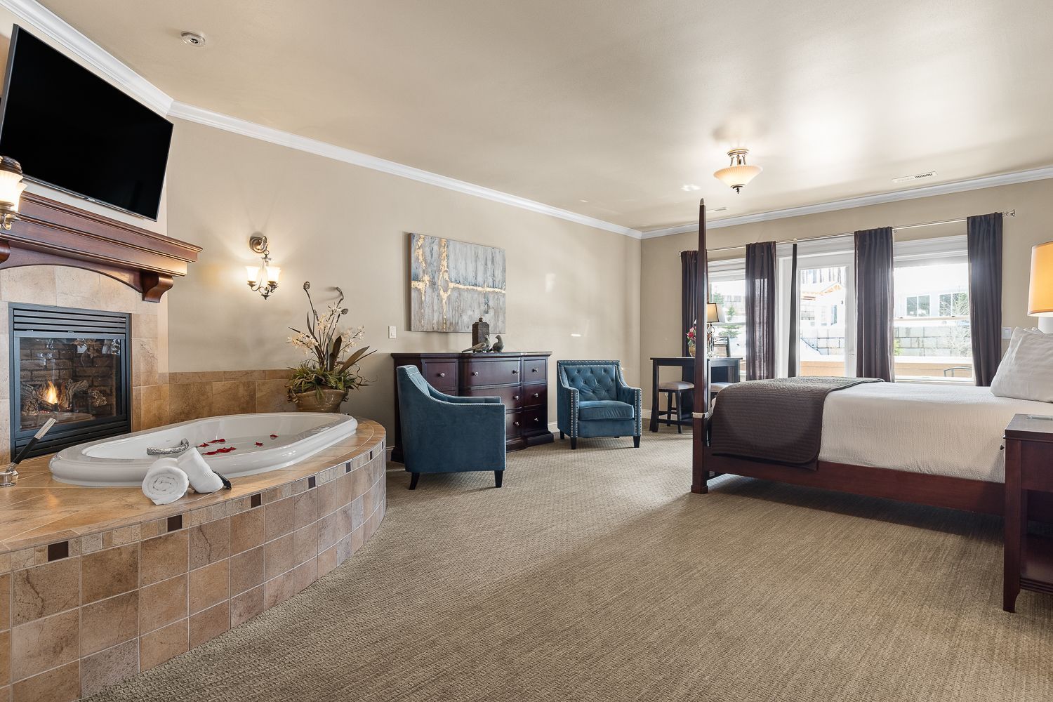 A hotel room with a king size bed , chairs , a fireplace and a jacuzzi.