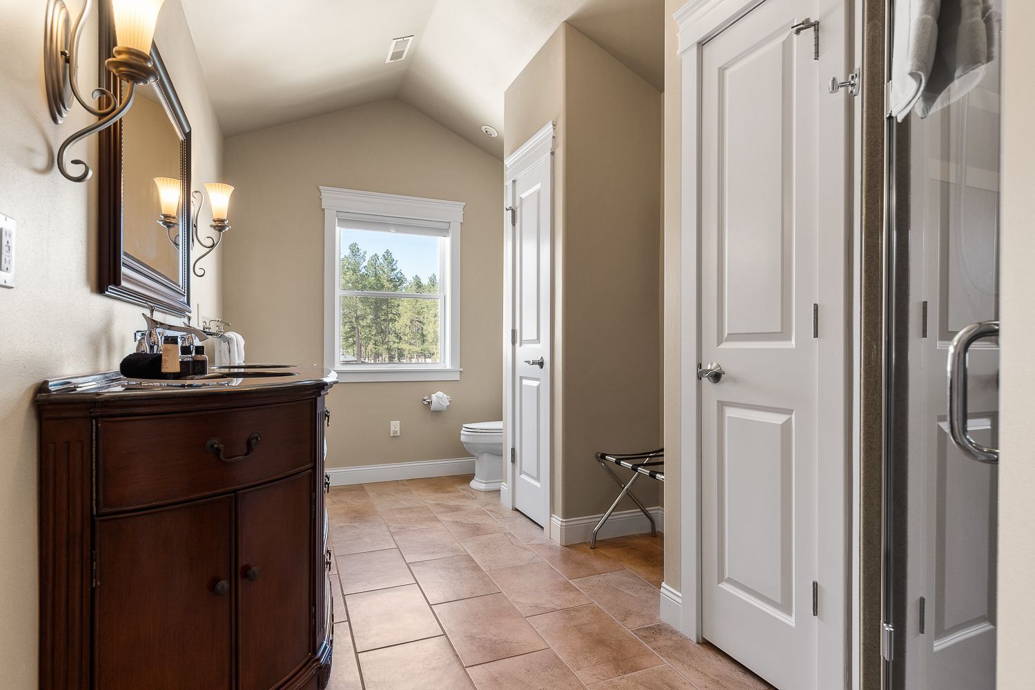 A bathroom with two sinks , a toilet , a mirror and a walk in shower.