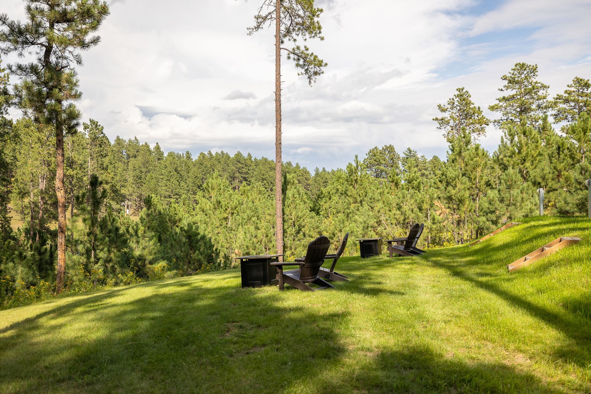 A fire pit in the middle of a lush green field with trees in the background.