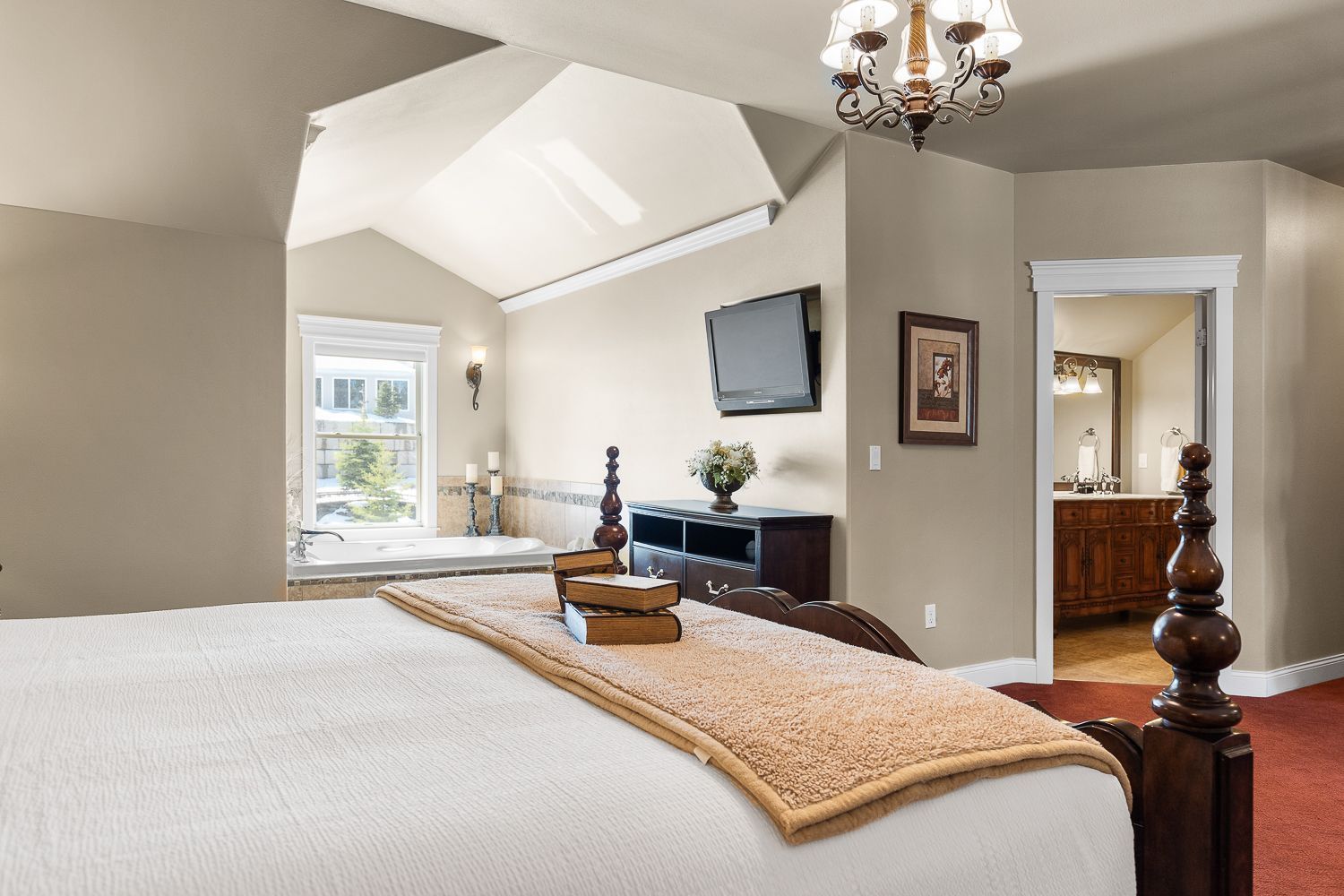 A bedroom with a large bed and a television on the wall