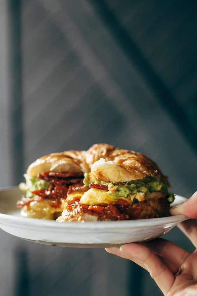 A person is holding a plate of food with a sandwich on it.