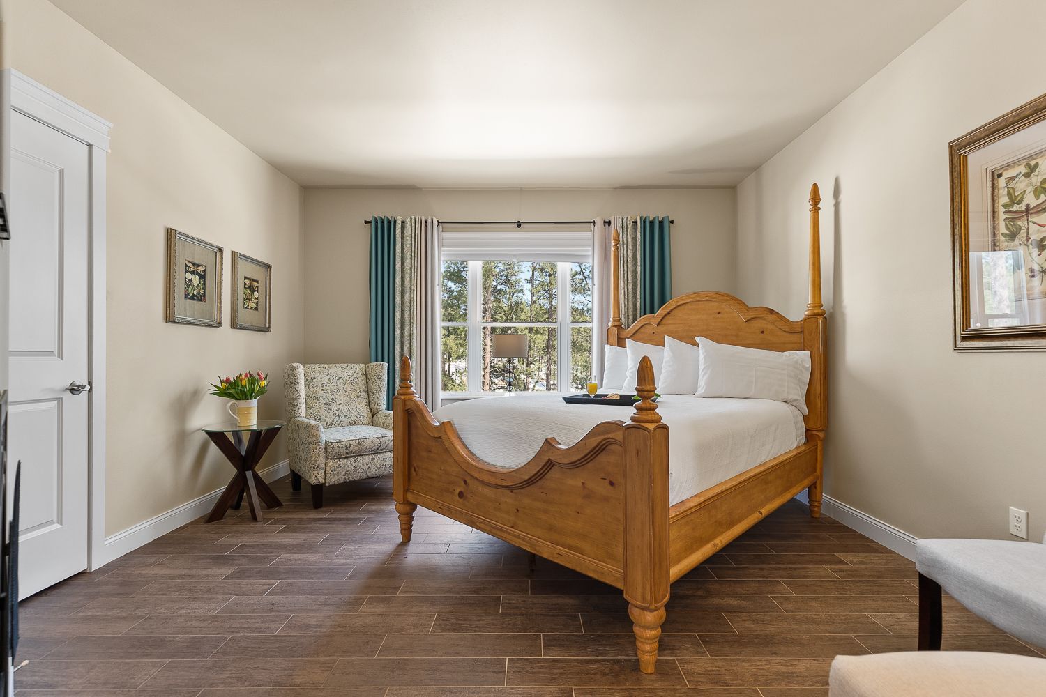 A bedroom with a king size bed , chair , table and window.