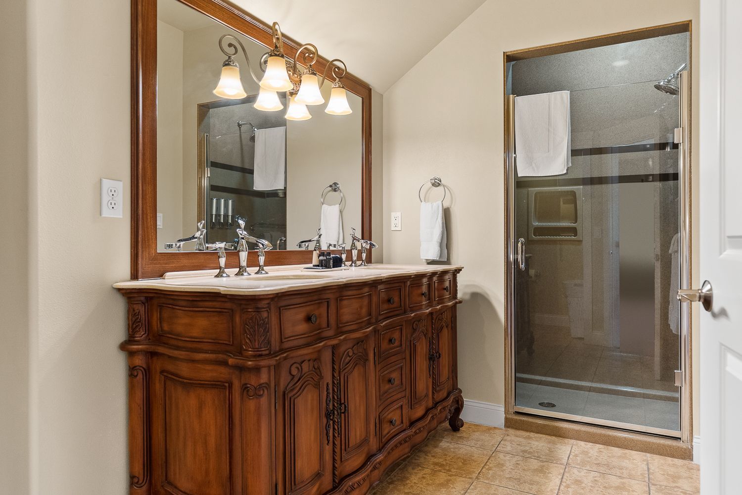 A bathroom with two sinks , a mirror and a walk in shower.