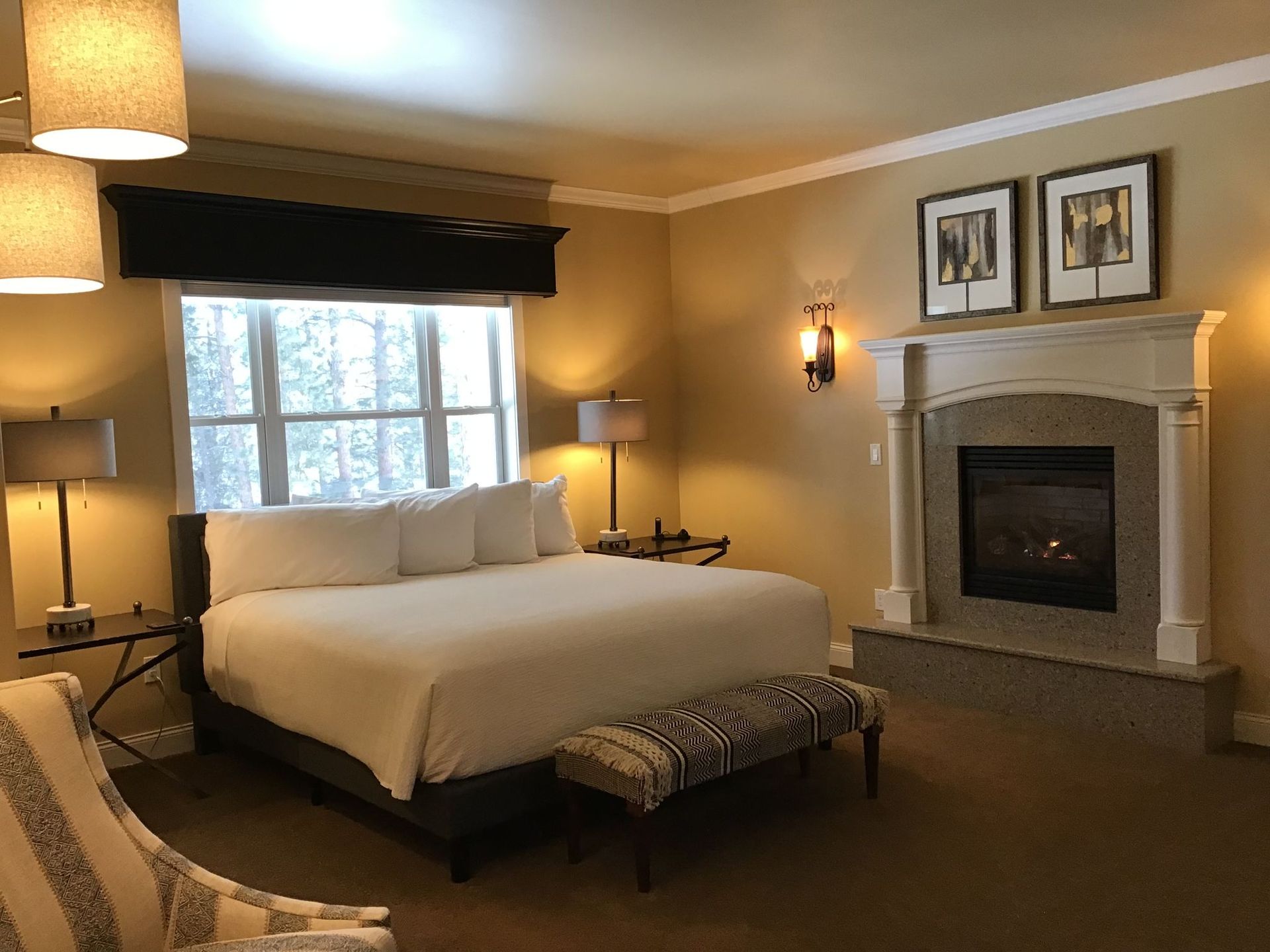 A hotel room with a king size bed and a fireplace.