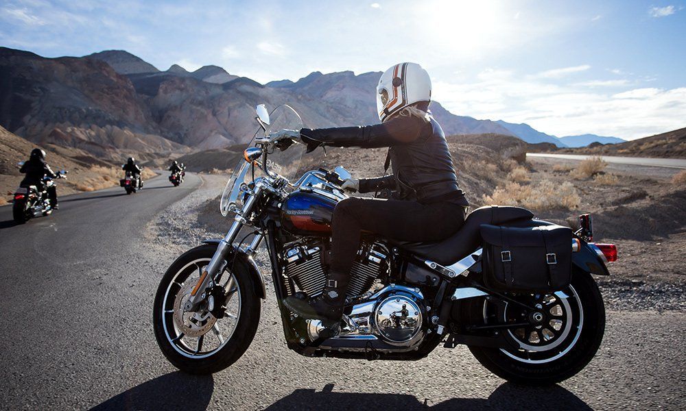 A man is riding a motorcycle down a desert road.