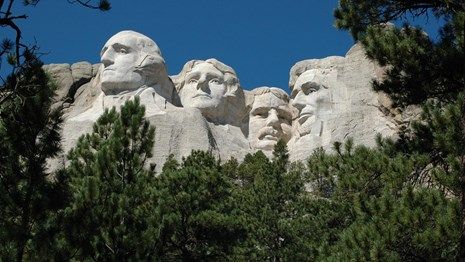 A statue of the presidents of the united states is surrounded by trees.