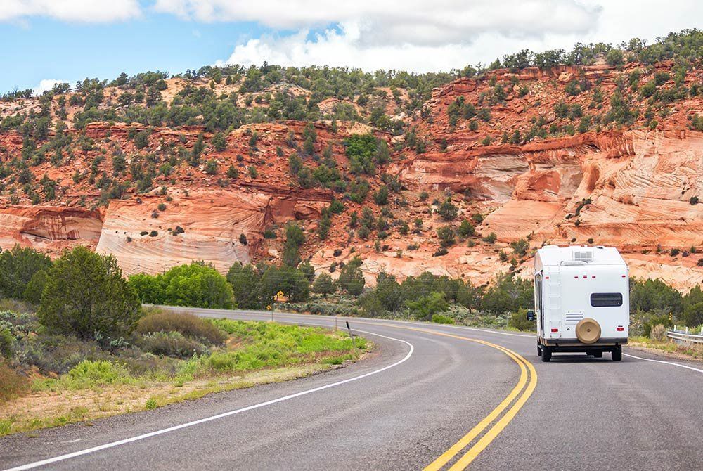 A white rv is driving down a curvy road.
