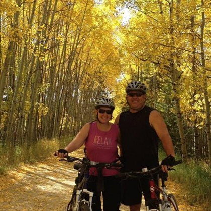 A man and a woman are standing next to each other on a bike trail.
