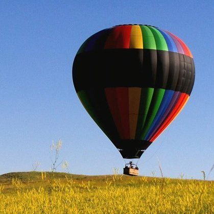 A colorful hot air balloon is flying over a field