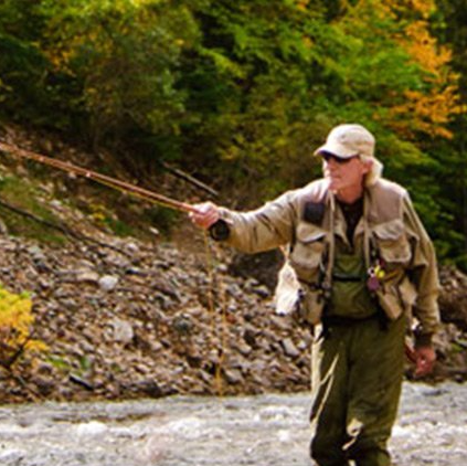 A man is fishing in a river with a fishing rod.