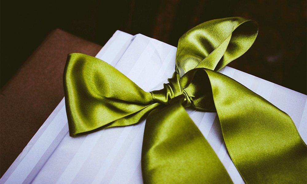 A white gift box with a green bow on it.