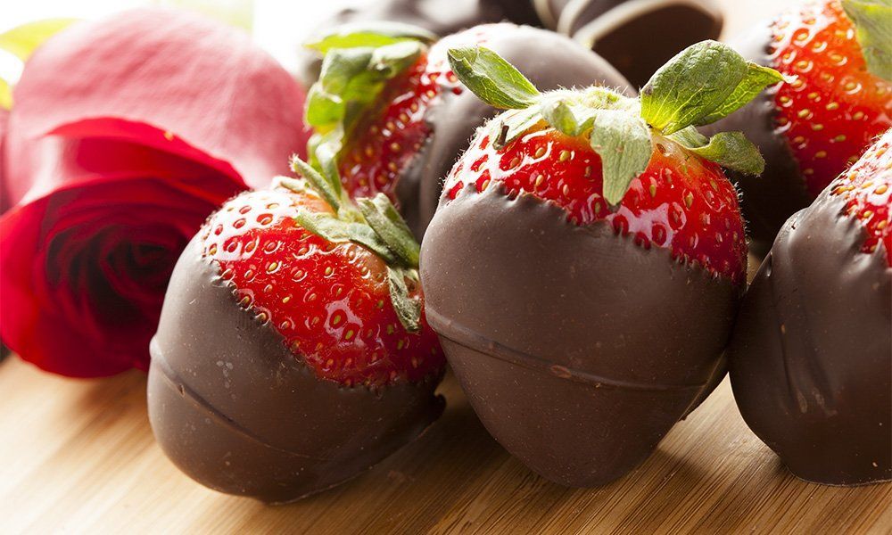 A bunch of chocolate covered strawberries on a wooden table