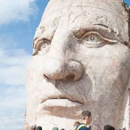 A group of people standing in front of a large statue of a man 's face