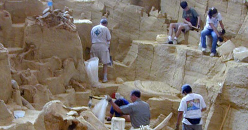 A group of people are working on a large rock formation.