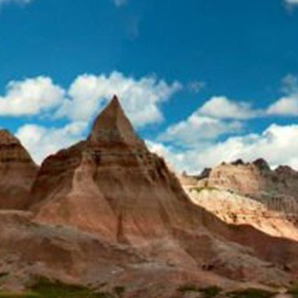 A mountain in the middle of a desert with a blue sky in the background.