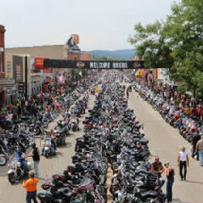 A large number of motorcycles are parked on the side of the road.