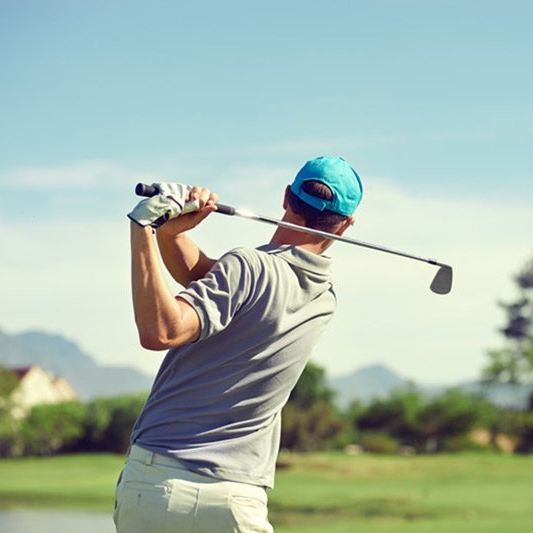 A man is swinging a golf club on a golf course