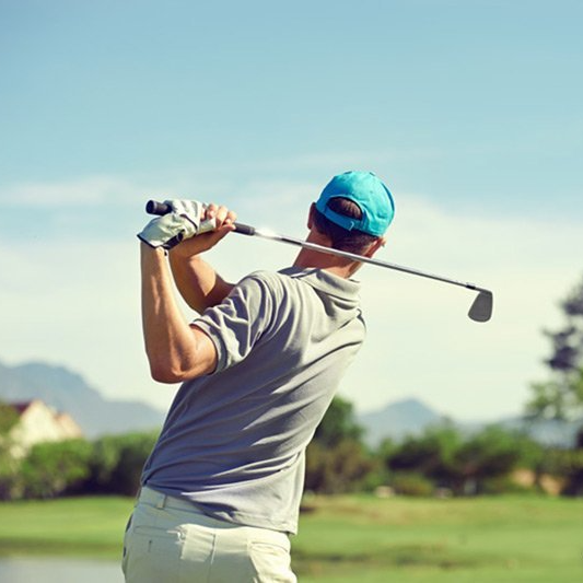 A man is swinging a golf club on a golf course