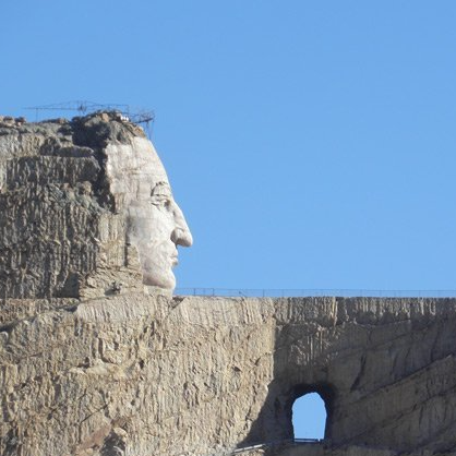 A statue of a man 's head on top of a rocky cliff