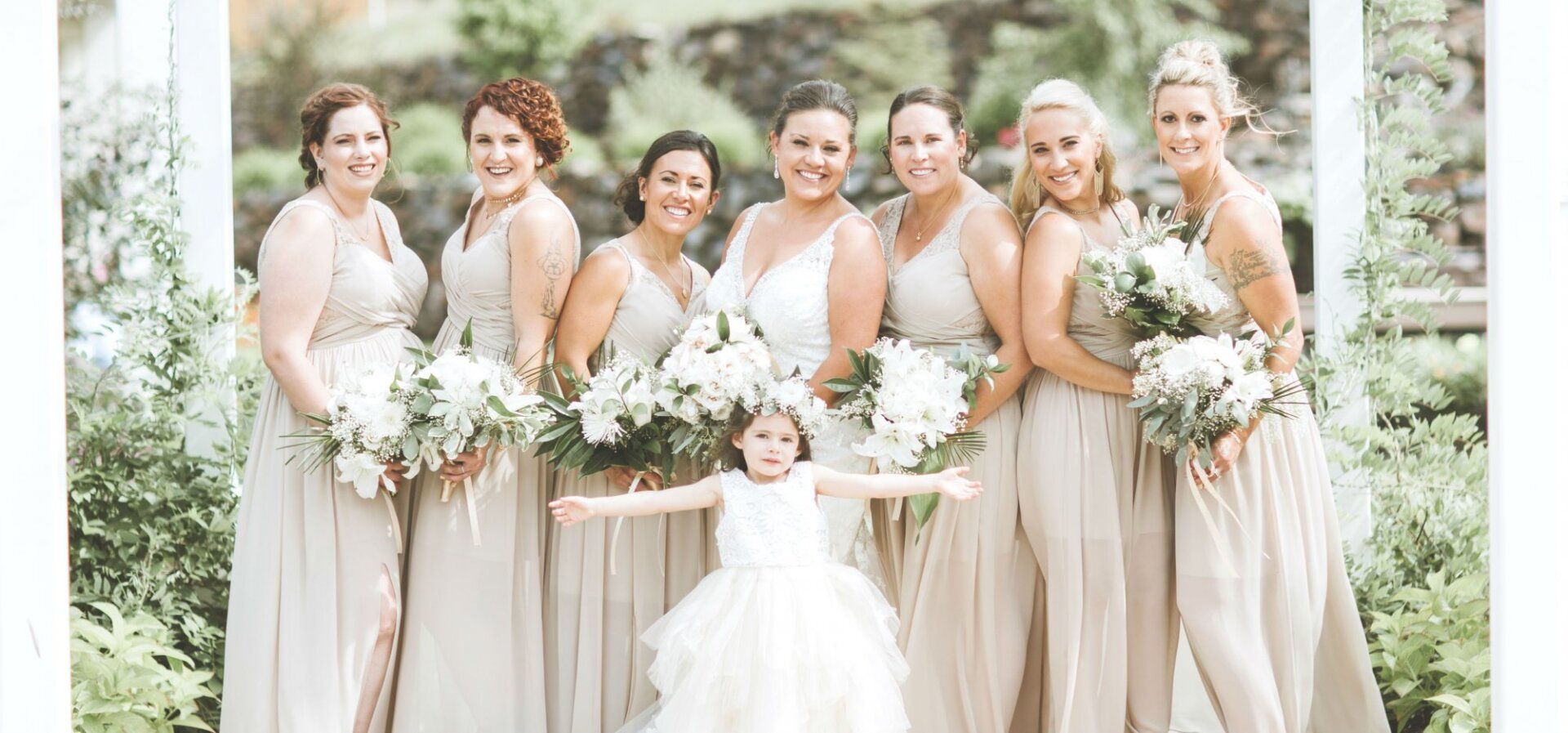 A bride and her bridesmaids are posing for a picture with a flower girl.