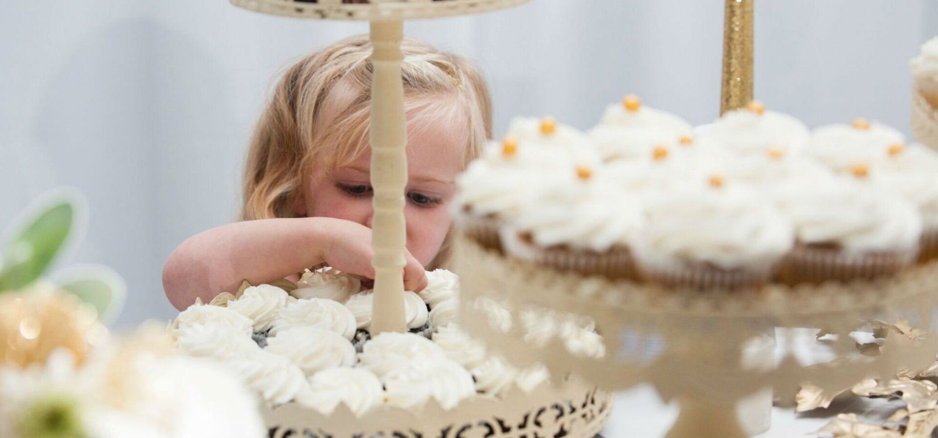 A little girl is putting a cupcake on top of a cake.