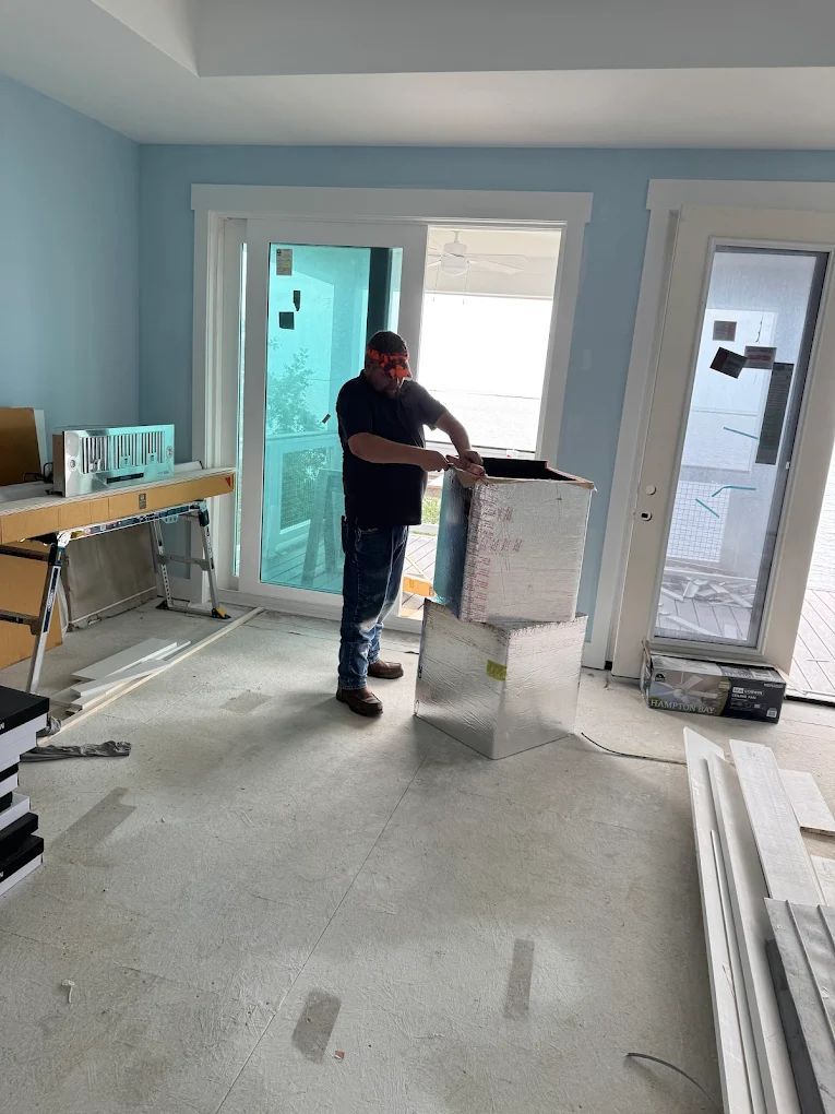 Man assembling HVAC ducts in a room with light blue walls and a sliding glass door.
