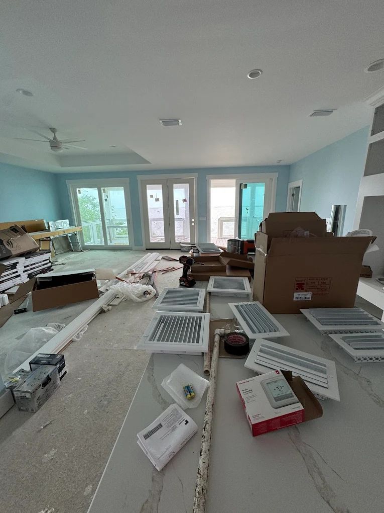 Construction site. Living room with light blue walls, supplies scattered on countertops, and doors leading outside.