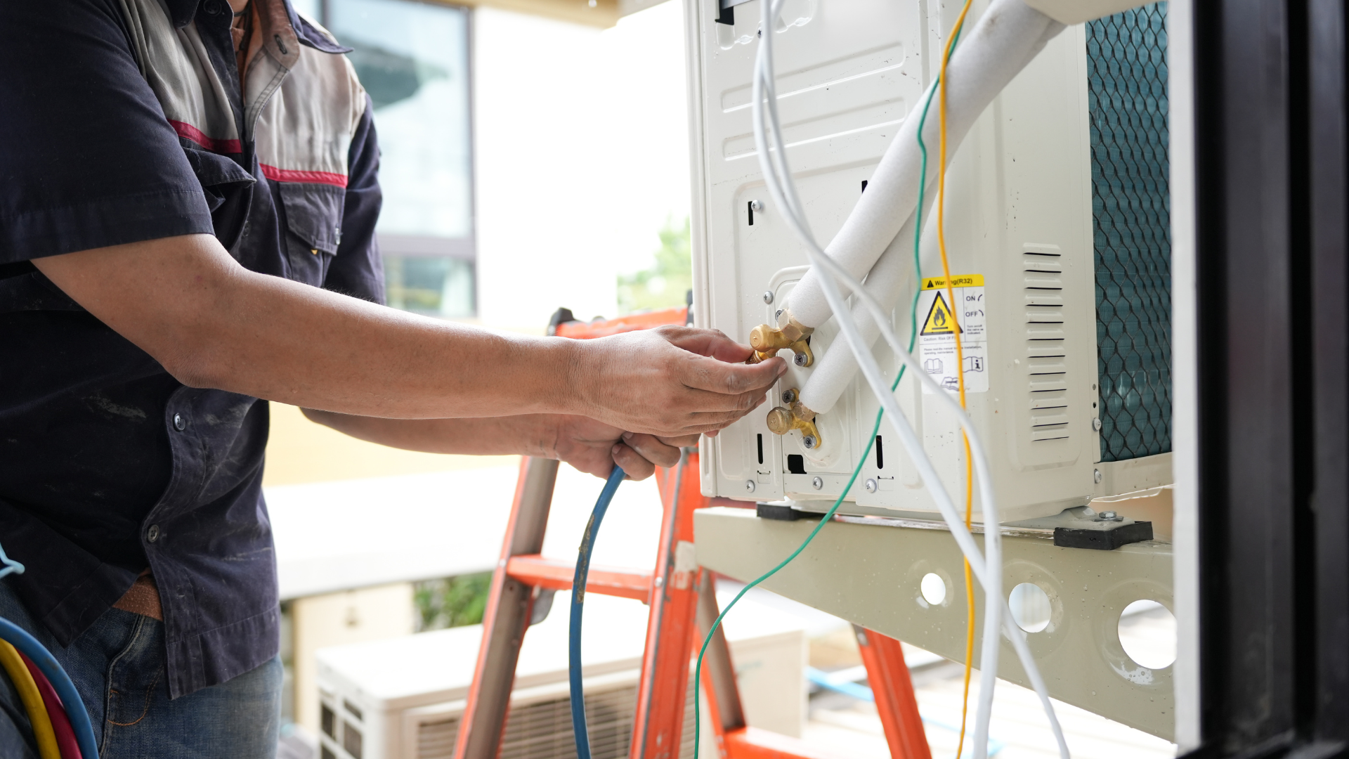 HVAC technician connecting tubes to an outdoor air conditioning unit.