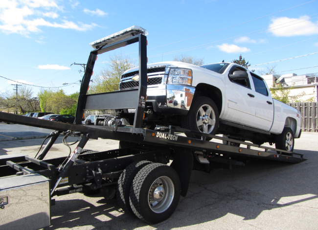 A white truck is being towed by a tow truck