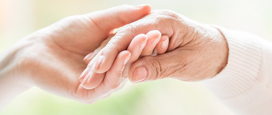 Nurse holding elderly person's hand