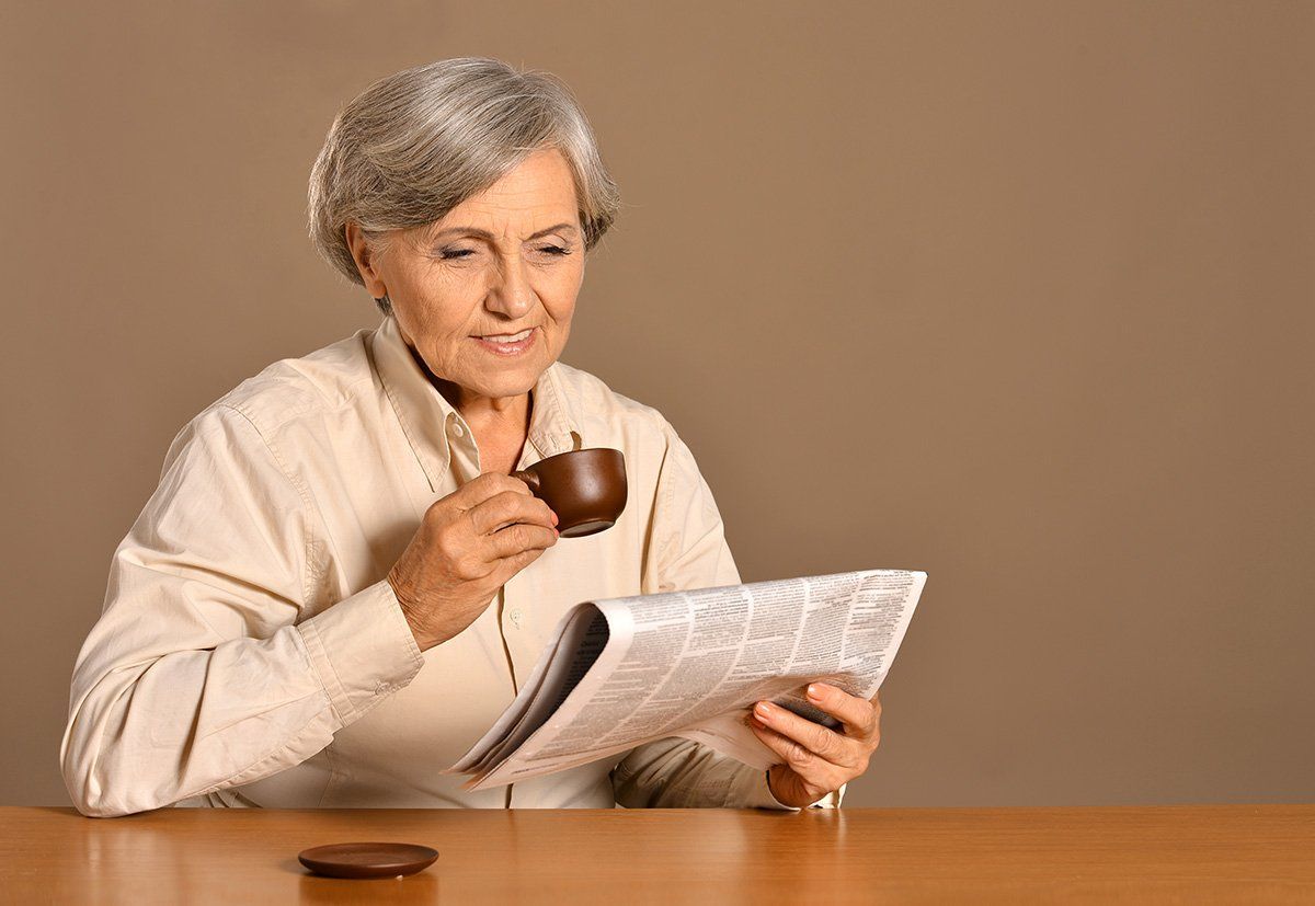 Elderly woman reading newspaper