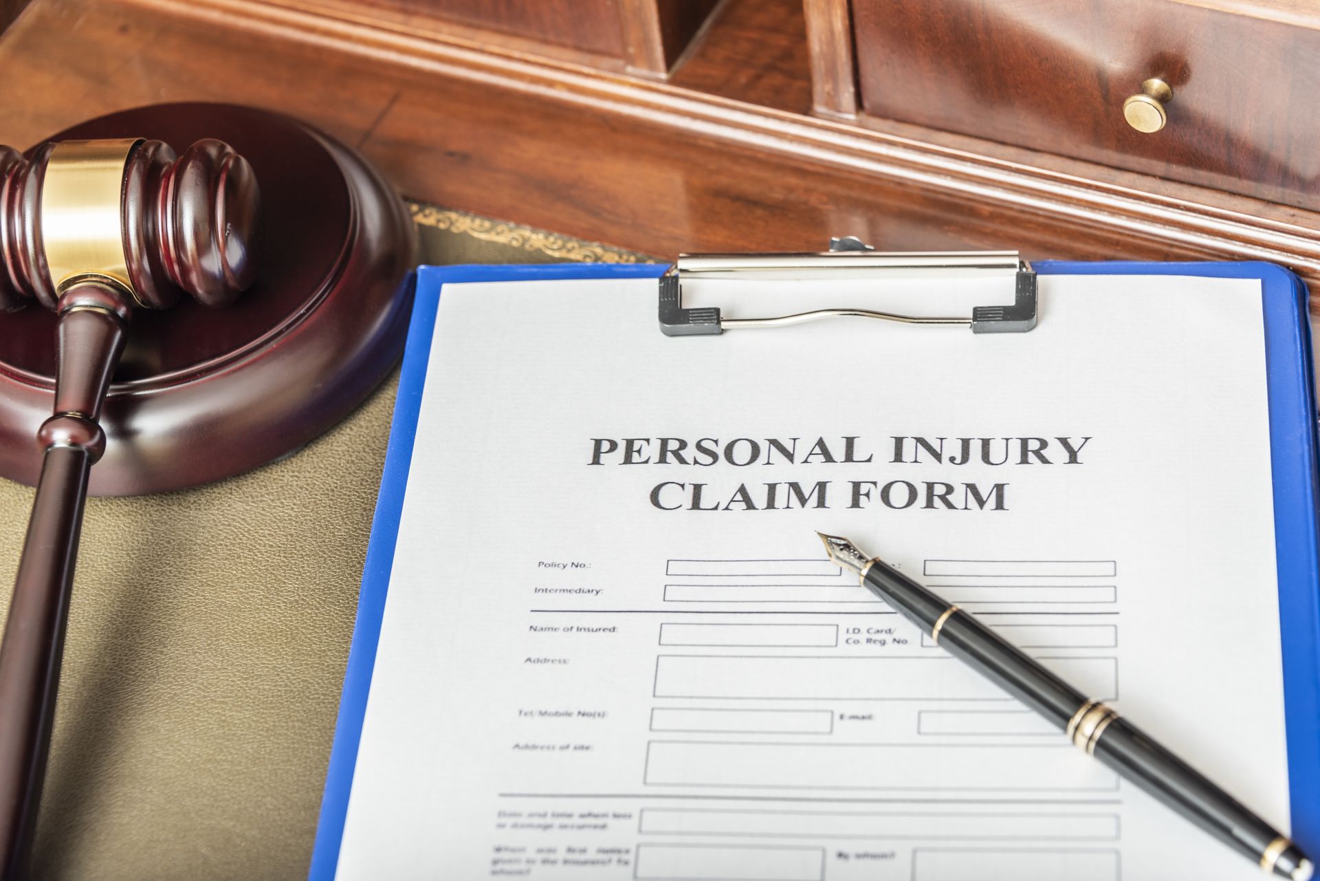 personal injury claim form on a blue clipboard with a pen resting on top, placed on a desk.
