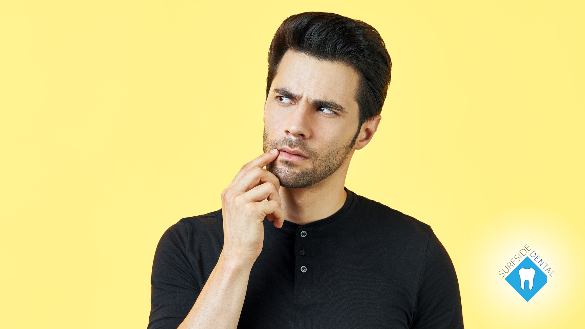 Man in black shirt, hand on chin, looking up thoughtfully against a yellow background.