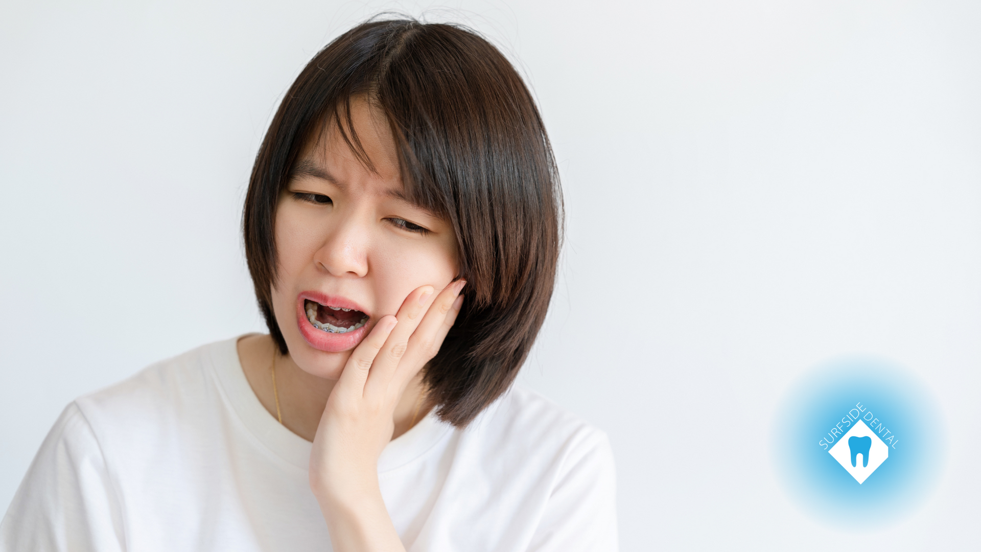 A woman is holding her mouth in pain because of a toothache.