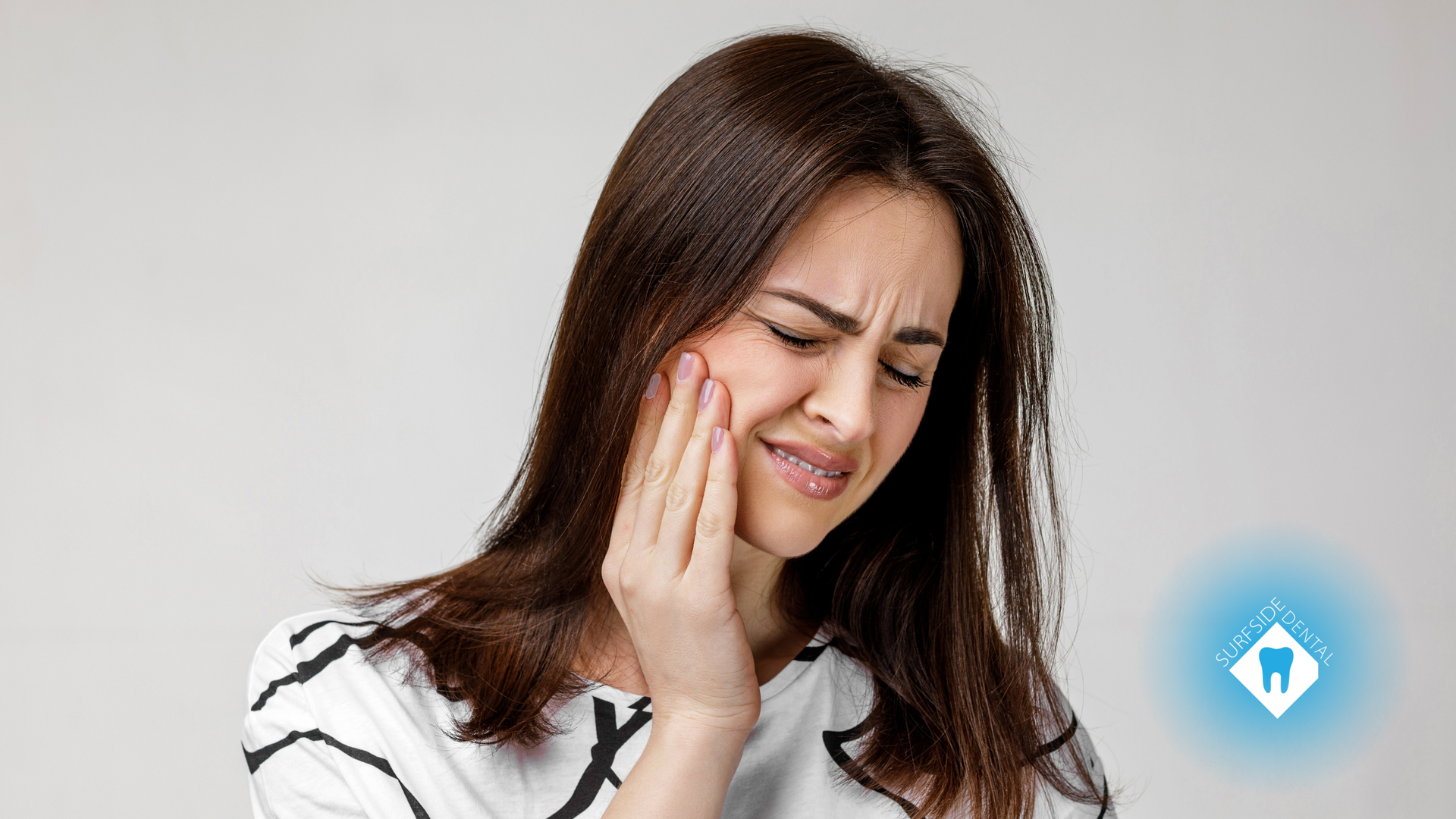 A woman is holding her face in pain because of a toothache.