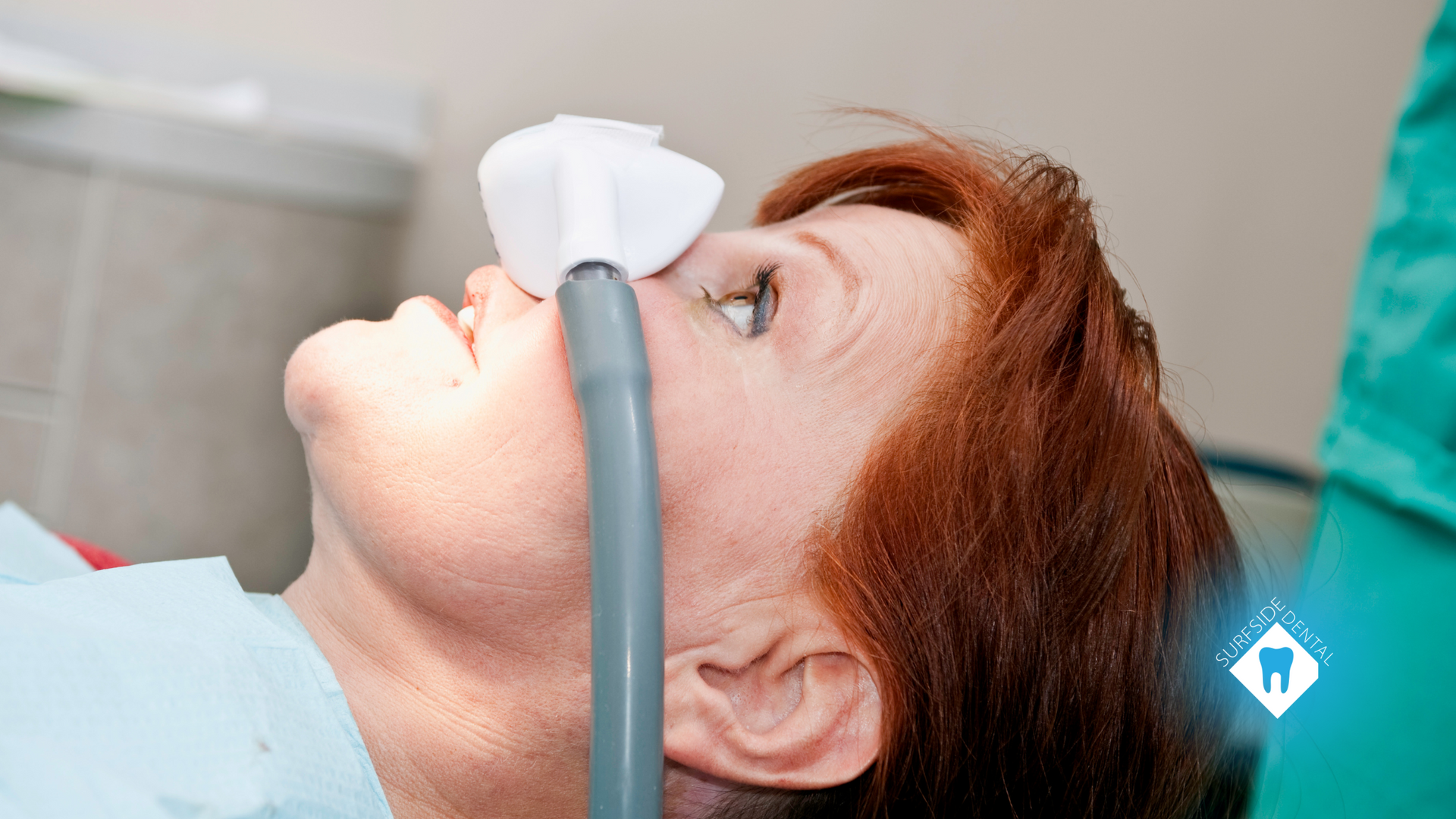 A woman is laying in a dental chair with an oxygen mask on her face.