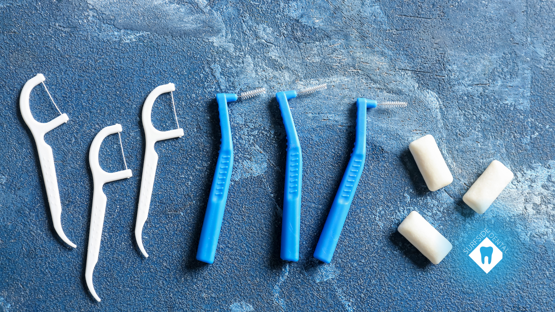 A row of dental floss and toothbrushes on a blue surface.