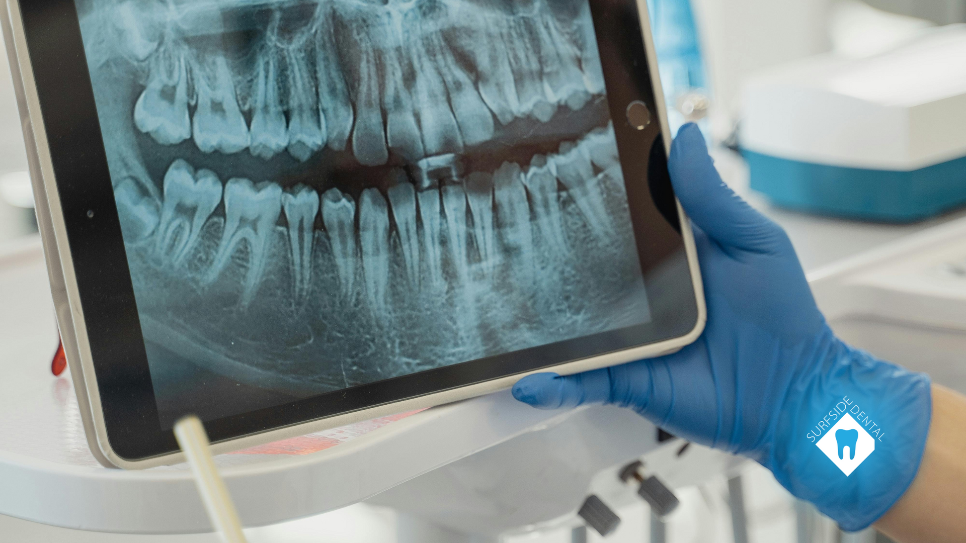 A dentist is holding a tablet with an x-ray of a person 's teeth on it.