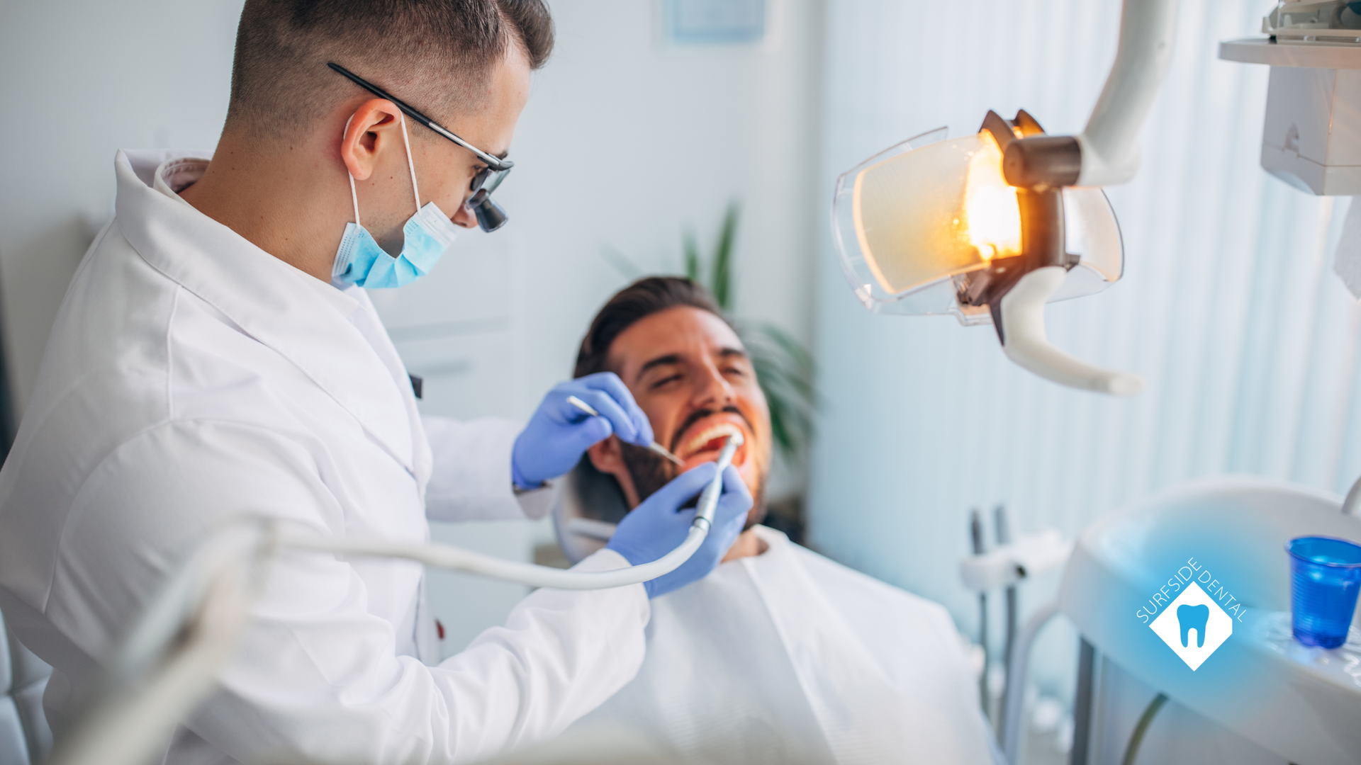 Dentist examining a patient's teeth under a bright light in a dental office.