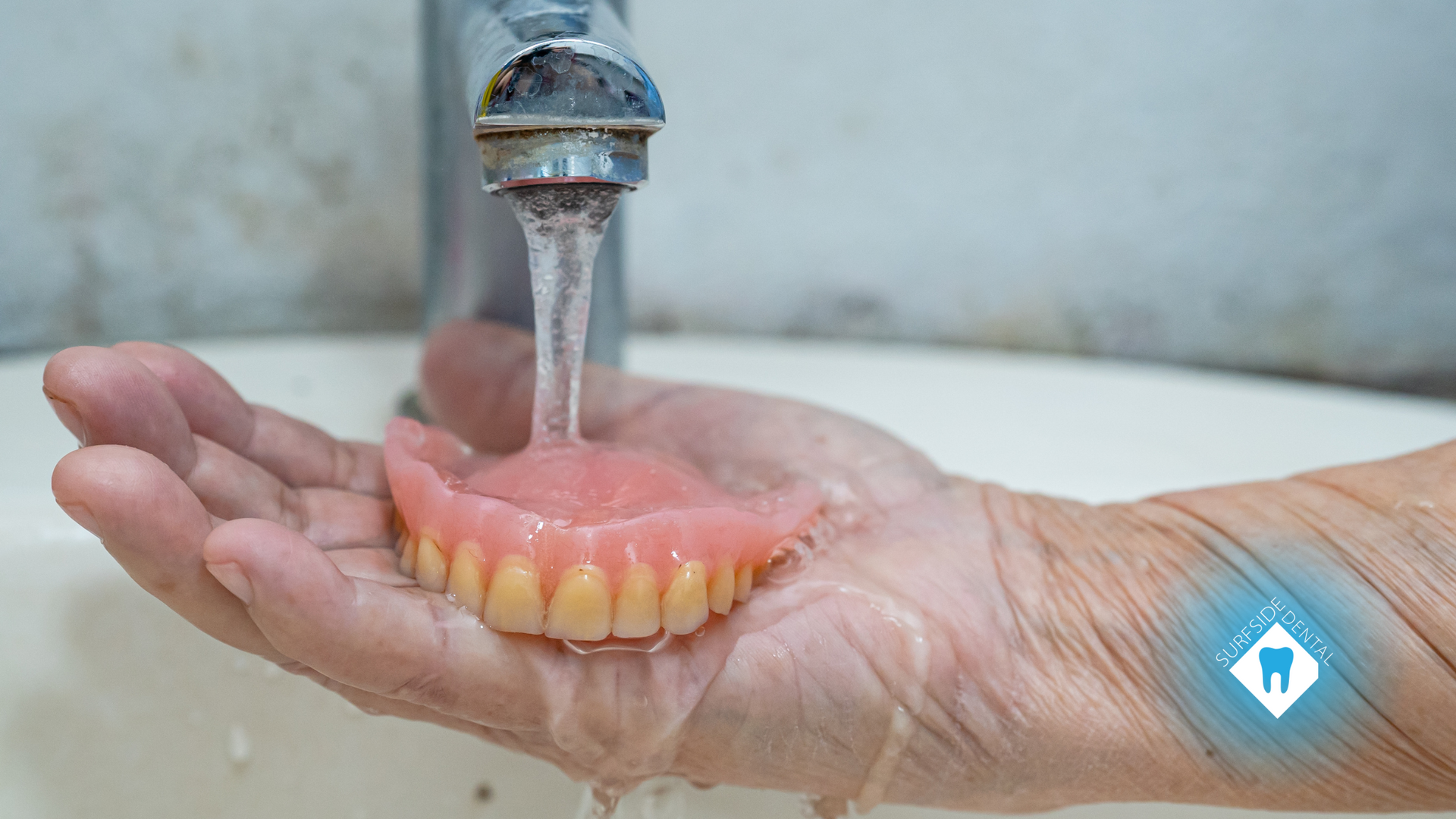 A person is washing a denture in a sink.