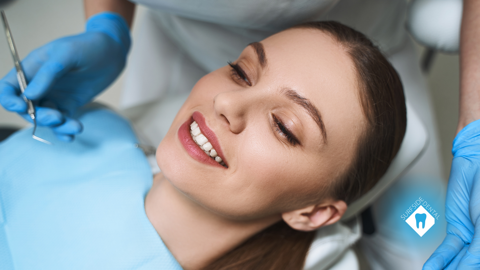 A woman is laying in a dental chair while a dentist examines her teeth.