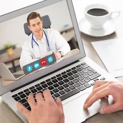Person on a laptop in a telehealth session with a doctor, typing with the hands.