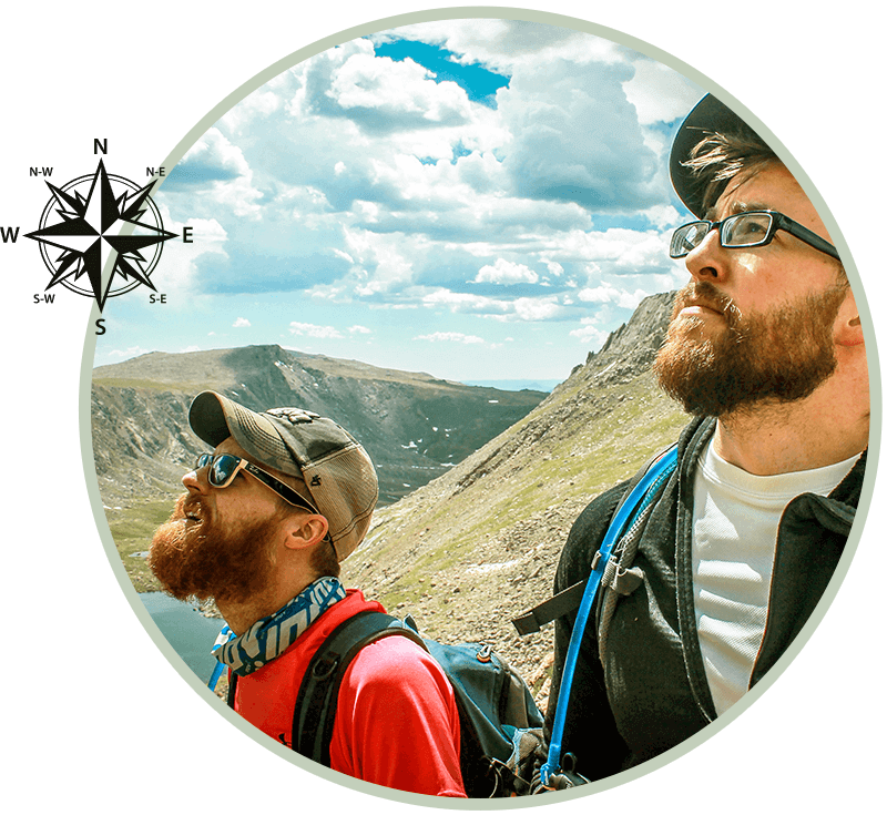 Two bearded hikers looking up at a mountain vista; blue sky, compass rose graphic.