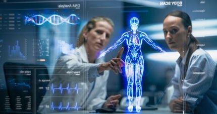 Two female scientists examine a 3D holographic model of a human body and data visualizations in a lab.