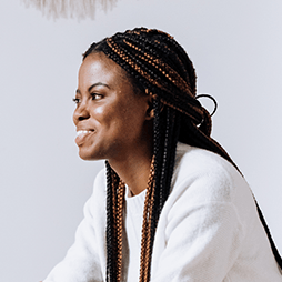 Woman with braided hair, smiling, wearing a white sweater.