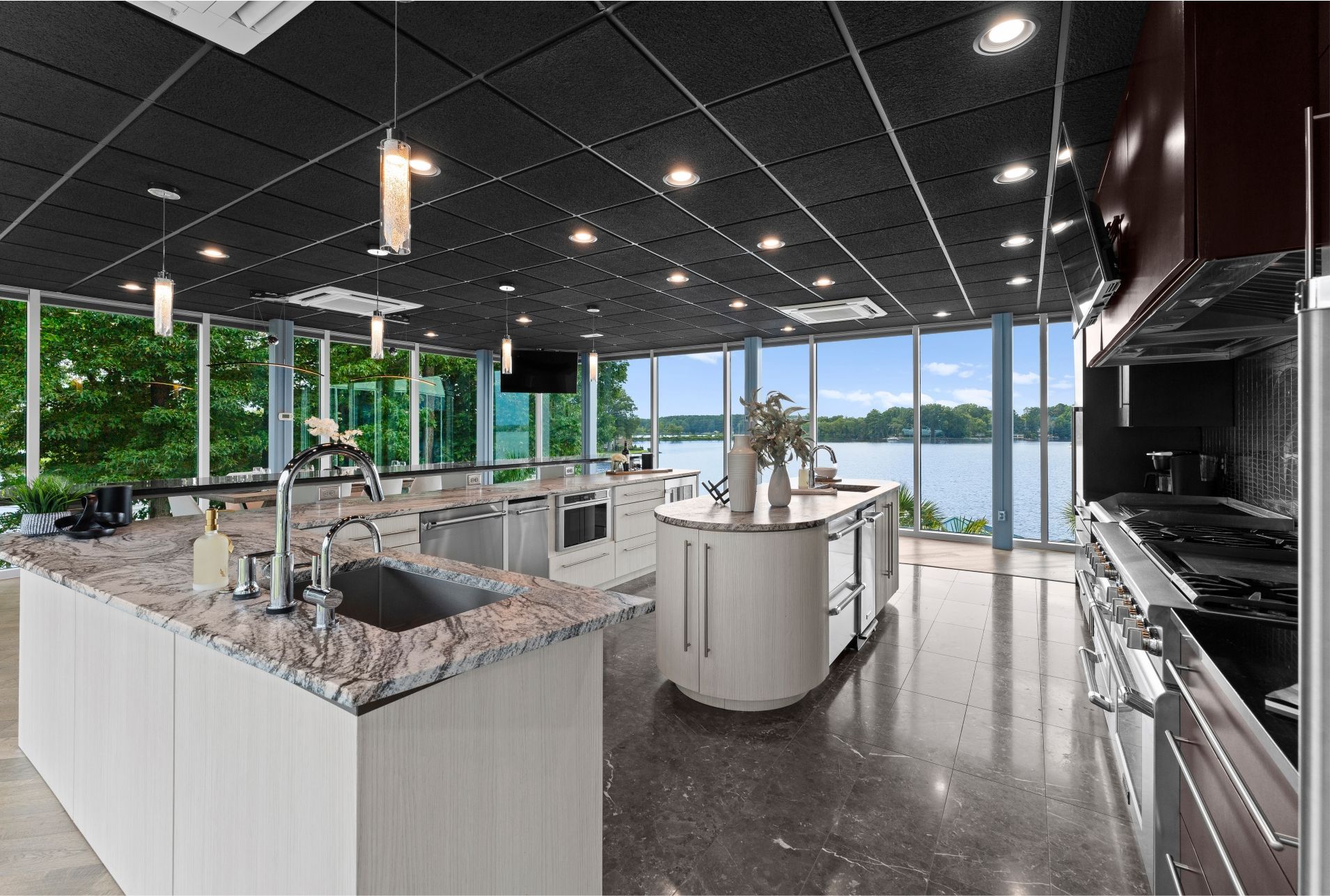 Modern kitchen with large windows overlooking a lake. Gray granite countertops, stainless steel appliances.