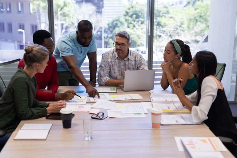 A group of people are sitting around a table having a meeting.