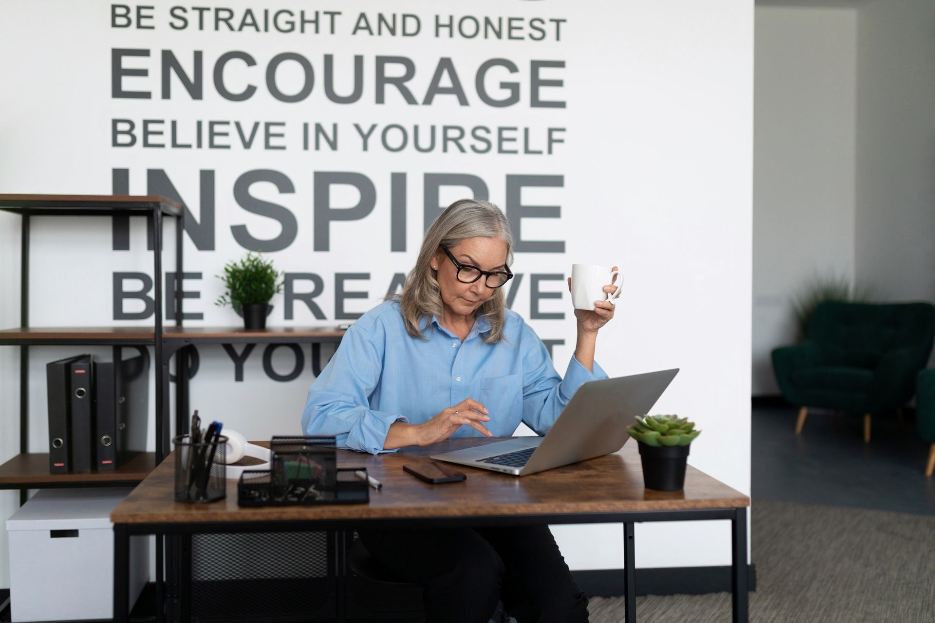 A woman is sitting at a desk using a laptop computer.