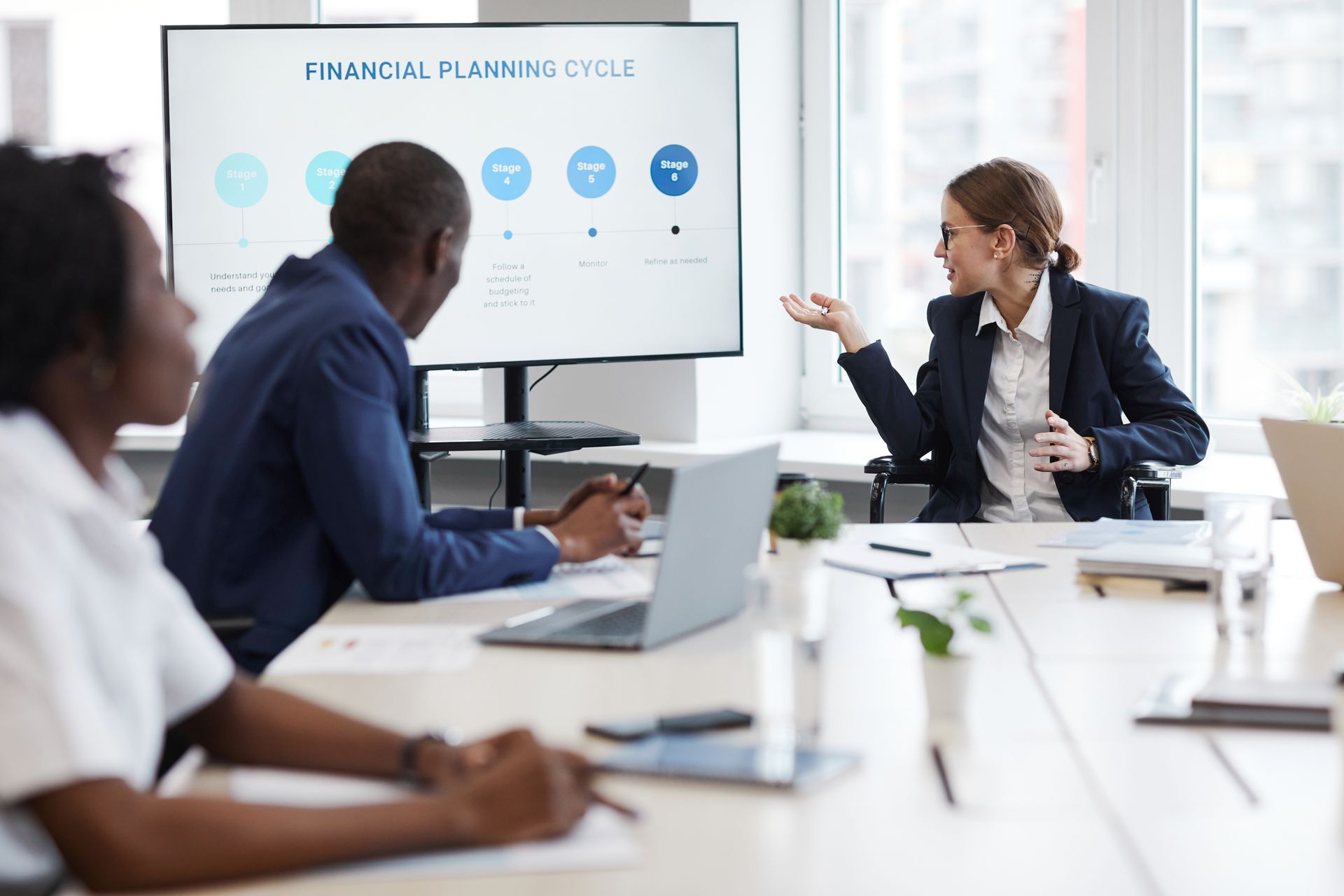 A woman is giving a presentation to a group of people in a conference room.