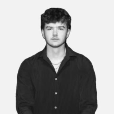 A young man in a black shirt is standing in front of a white background.